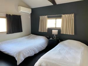 a bedroom with two beds and two windows at Samurai Suite 1 , 15mins from Kyoto Eki , 5 mins to Arashiyama in Kyoto