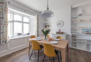a dining room with a wooden table and yellow chairs at Gurnard Cottage in Niton