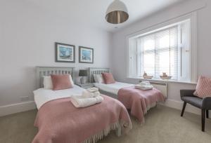 a bedroom with two beds with pink and white sheets at Gurnard Cottage in Niton