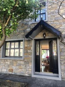 a stone house with a black door and windows at 4 Harbour Town House in Westport