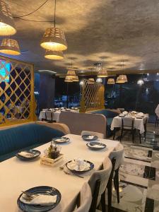 un comedor con mesas, sillas y lámparas de araña en HOTEL BAR RESTORANT YLLI en Shëngjin