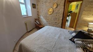 a bedroom with a bed and a stone wall at Le Petit Cocon in Vénéjan