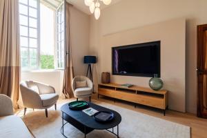uma sala de estar com uma televisão e uma mesa e cadeiras em Luxueux Appt dans un chateau à Aix em Châteauneuf-le-Rouge