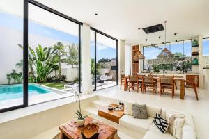 チャングーにあるCasa Umalas Villa by Betterplaceの大きな窓のあるオープンリビングルームとダイニングルーム