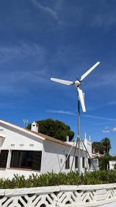 a white house with a windmill in front of it at Casa Eucaliptus in L'Eucaliptus