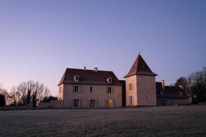 un gran edificio de ladrillo con una torre en un campo en Domaine Truffier du Grand Merlhiot en Savignac-les-Églises
