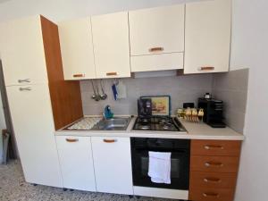 Elle comprend une petite cuisine avec des placards blancs et un évier. dans l'établissement CASA VACANZA POLI, à Ascoli Piceno