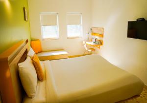 a bedroom with a white bed and a television at Bloom Hotel - Calangute in Calangute