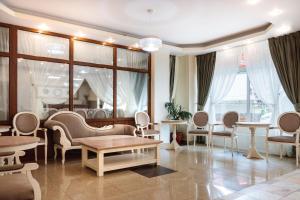 ein Wohnzimmer mit Stühlen, Tischen und Fenstern in der Unterkunft Hotel Central - Baile Olanesti in Băile Olăneşti