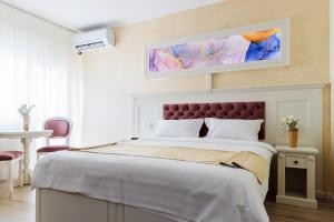 Un dormitorio con una cama grande con una pintura encima. en Hotel Central - Baile Olanesti en Băile Olăneşti