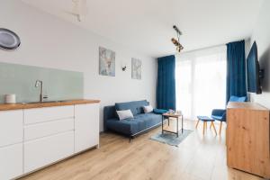 cocina y sala de estar con sofá azul en Apartamenty Mierzeja NCNK Baltic Garden Sztutowo en Sztutowo