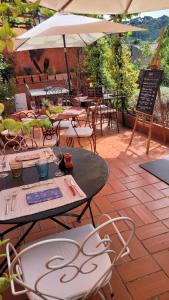 un patio con mesas, sillas y una sombrilla en Le Belvédère - Chambres d'hôtes de charme et Restaurant, en Flassans-sur-Issole