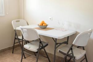 a white table with chairs and a bowl of fruit on it at Margaret Apartments in Lefkimmi +9 photos