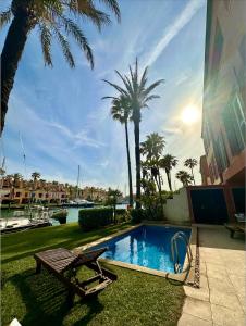 a swimming pool with a bench and palm trees at Casa Arlequin in Sotogrande