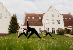 eine Gruppe von Leuten, die Yoga im Gras machen in der Unterkunft Hotel-Garni Gut Tribbevitz in Neuenkirchen auf Rügen