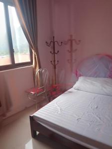 een slaapkamer met een bed, een stoel en een raam bij Huy Nhung Homestay in Ha Giang