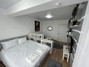 Habitación blanca con cama y escritorio en Perla Home - Studio 22, en Popeşti-Leordeni