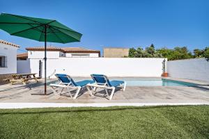 twee stoelen en een parasol naast een zwembad bij Villa Jero in Chiclana de la Frontera