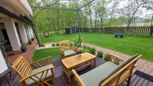 a patio with a wooden table and chairs and a yard at TücsökTanya Vendégház in Csemő