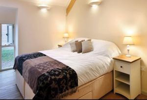 1 dormitorio con 1 cama blanca grande y mesita de noche en Blagdon Lower Barn, en Winterborne Steepleton