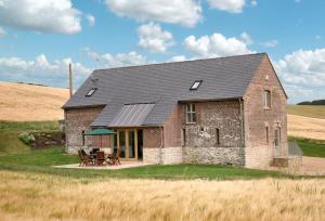 a brick house with a black roof in a field at Blagdon Lower Barn in Winterborne Steepleton