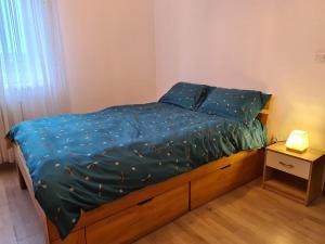 a bed with a blue comforter and a night stand at Central Cosy Apart Oradea in Oradea