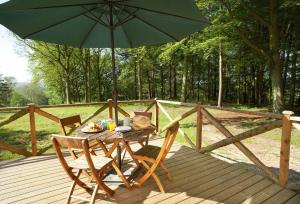 a table and chairs with an umbrella on a wooden deck at Deerpark Lodge in Ashby de la Zouch