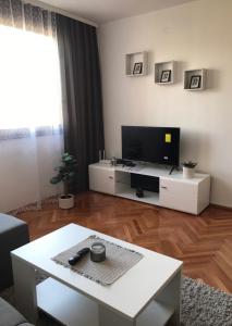 a living room with a flat screen tv and a table at Apartman Snezana in Pirot