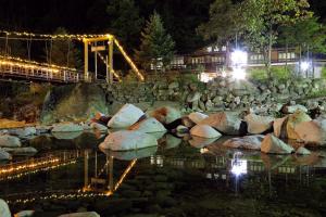 a bridge over a river at night with lights at Shinzanso in Takayama