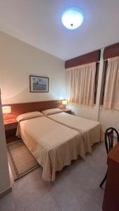 a bedroom with two beds and a table and two lamps at Il Nocchiero City Hotel in Soverato Marina