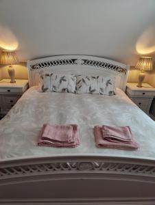 a white bed with two pink towels on it at Maggies Cottage in Manorhamilton