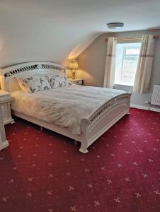 a bedroom with a large white bed with a red carpet at Maggies Cottage in Manorhamilton