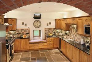 a kitchen with wooden cabinets and a clock on the wall at Llancayo Windmill in Monkswood