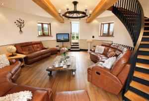 a living room with brown leather furniture and a staircase at Llancayo Windmill in Monkswood