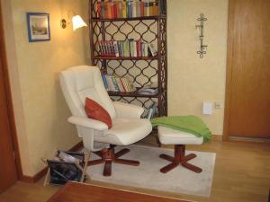 - un salon avec une chaise blanche et une étagère dans l'établissement Am Klecker Wald, Ferienhaus, à Jesteburg