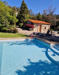 una piscina con 2 sillas y una casa en Casa dos três rapazes en Monte Córdova