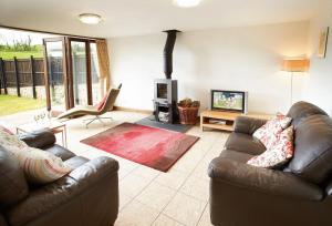 a living room with two leather couches and a fireplace at Hunters Moon in Honiton
