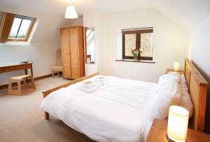 Un dormitorio con una gran cama blanca y una ventana en Hunters Moon, en Honiton