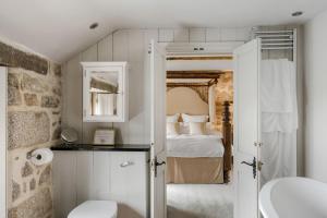 a bathroom with a bedroom with a bed and a toilet at Tregadjack Farmhouse in Crowan