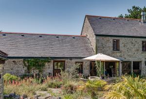 a stone house with an umbrella in front of it at Tregadjack Barn in Crowan