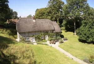 an old house with a thatched roof on a lawn at Magna Cottage in Ashmore