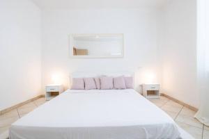 ein weißes Schlafzimmer mit einem weißen Bett und 2 Tischen in der Unterkunft -Villa Emily- Parking, Garden & Wi-Fi in Pisa