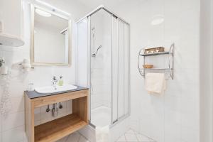 ein weißes Bad mit einem Waschbecken und einer Dusche in der Unterkunft Appartement Oberwirt Ferienwohnung in Ebbs