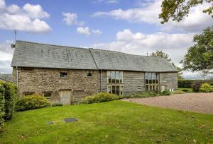 uma antiga casa de pedra com um jardim de relva em Wall Hills Barn em Bromyard