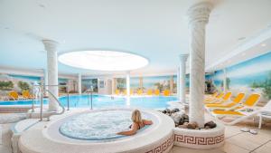 eine Darstellung eines Pools mit einem Mädchen in einem Whirlpool in der Unterkunft Arkona Strandhotel in Binz