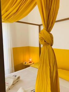 una camera con letto con tenda gialla di Le Stanze Di Brando E Nico a Tricase