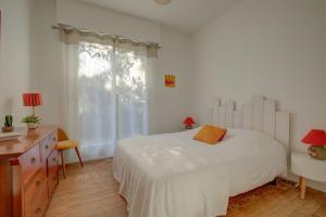 een slaapkamer met een wit bed, een bureau en een raam bij Abatille house in Arcachon