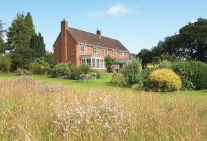 a large brick house with a field in front of it at The Oaks in All Stretton