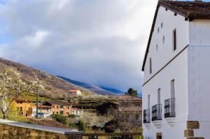 a white building with a mountain in the background at Hotel Valle del Jerte in Jerte