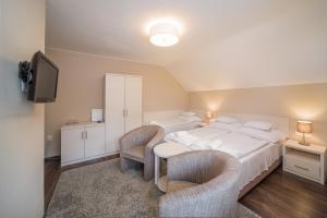 a bedroom with a bed with two chairs and a tv at Tokajer Wellness Panzió in Keszthely